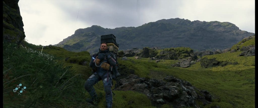 Sam Porter Bridges posant sur à flanc de colinne dans Death Stranding PC
