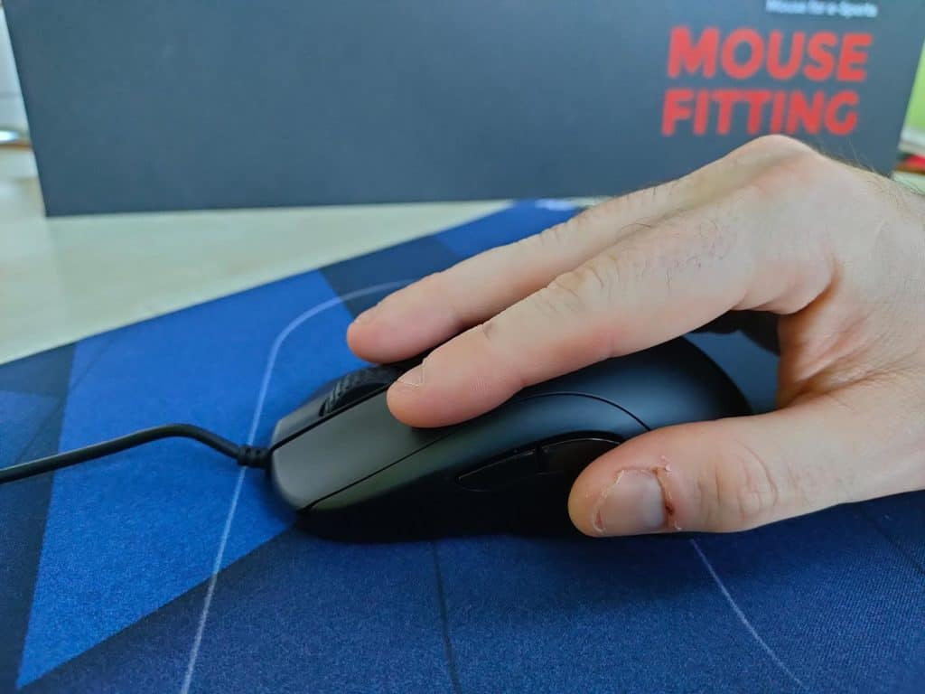 Une main tenant une des souris de la gamme Zowie série ZA