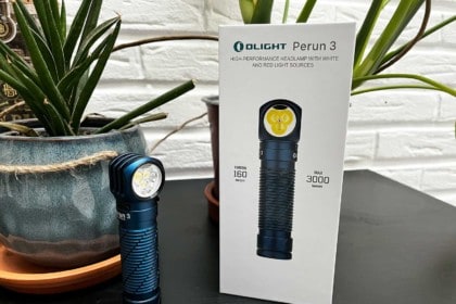 La lampe Olight Perun 3 posée sur une table à côté de sa boite
