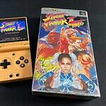 La Miyoo Mini Flip à côté d'un jeu vidéo