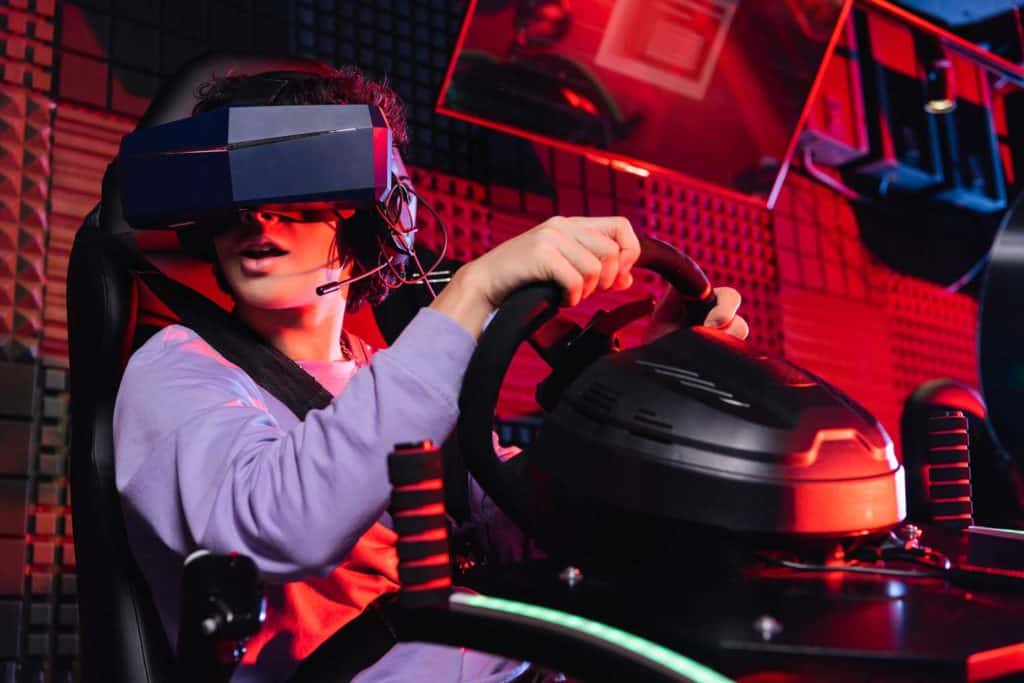 Un garçon jouant à un jeu de course au volant avec un casque VR