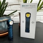 La lampe Olight Perun 3 posée sur une table à côté de sa boite